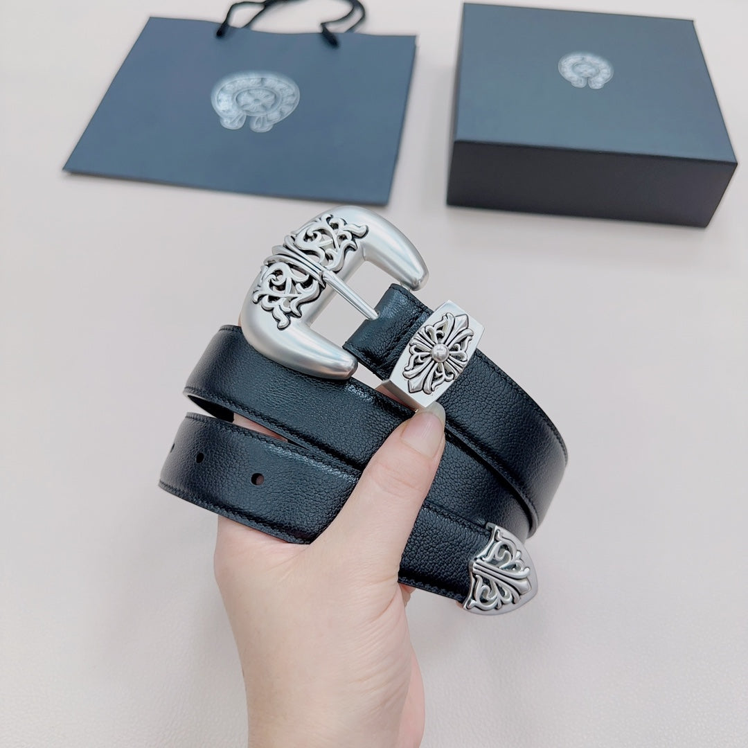 Hand holding dark blue leather belt featuring silver buckle with ornate engraved cross motifs.