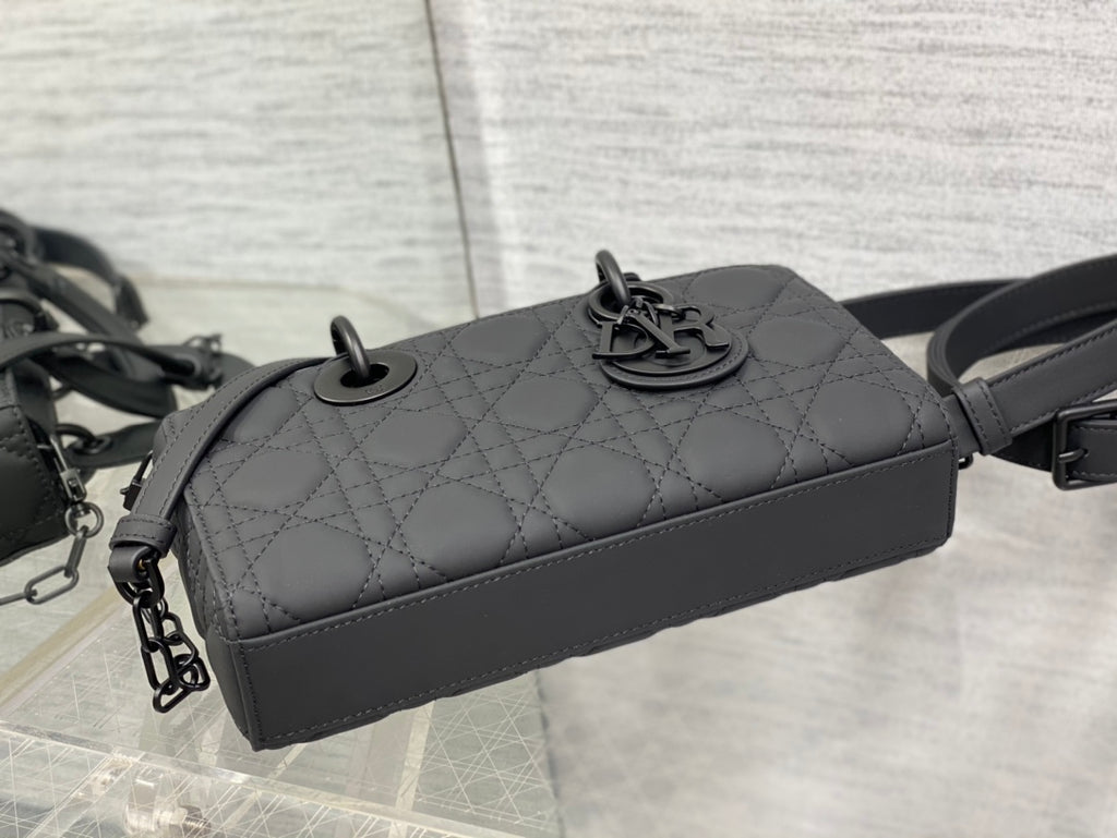 Black quilted handbag top with central emblem and shoulder strap