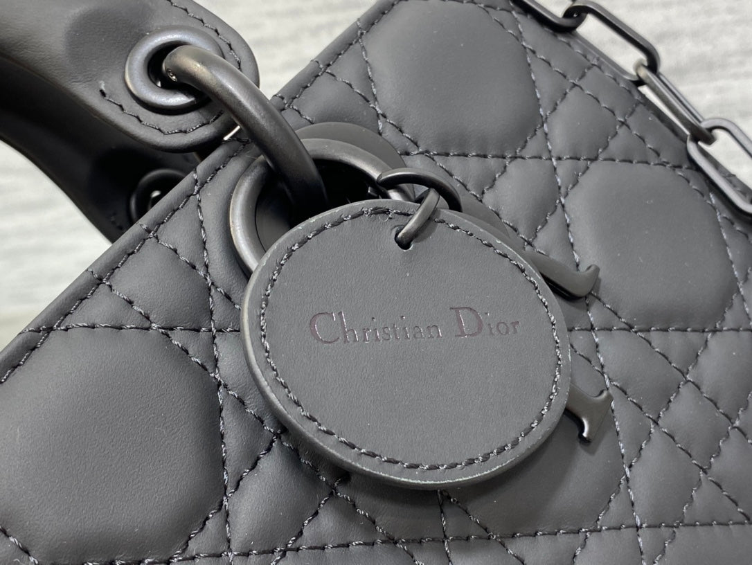 Black quilted handbag charm tag reading “Christian Dior”