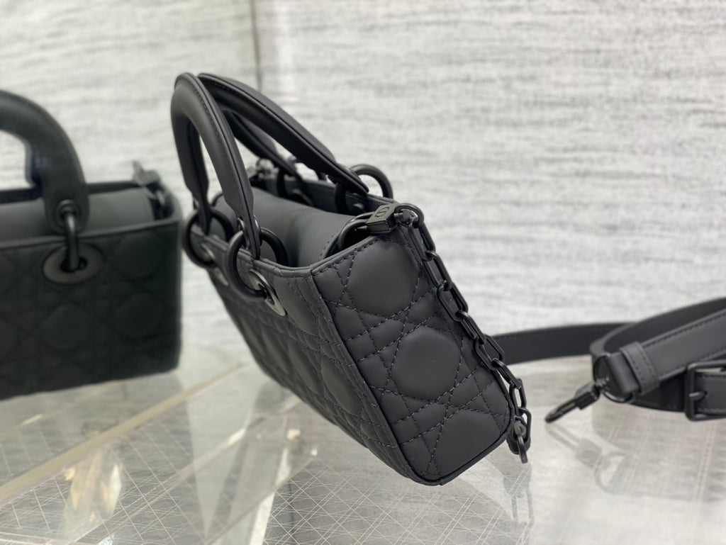 Black quilted handbag side view with chain link strap and handle