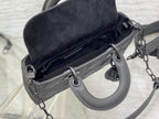Black handbag open top with gray-lined interior and metal strap rings