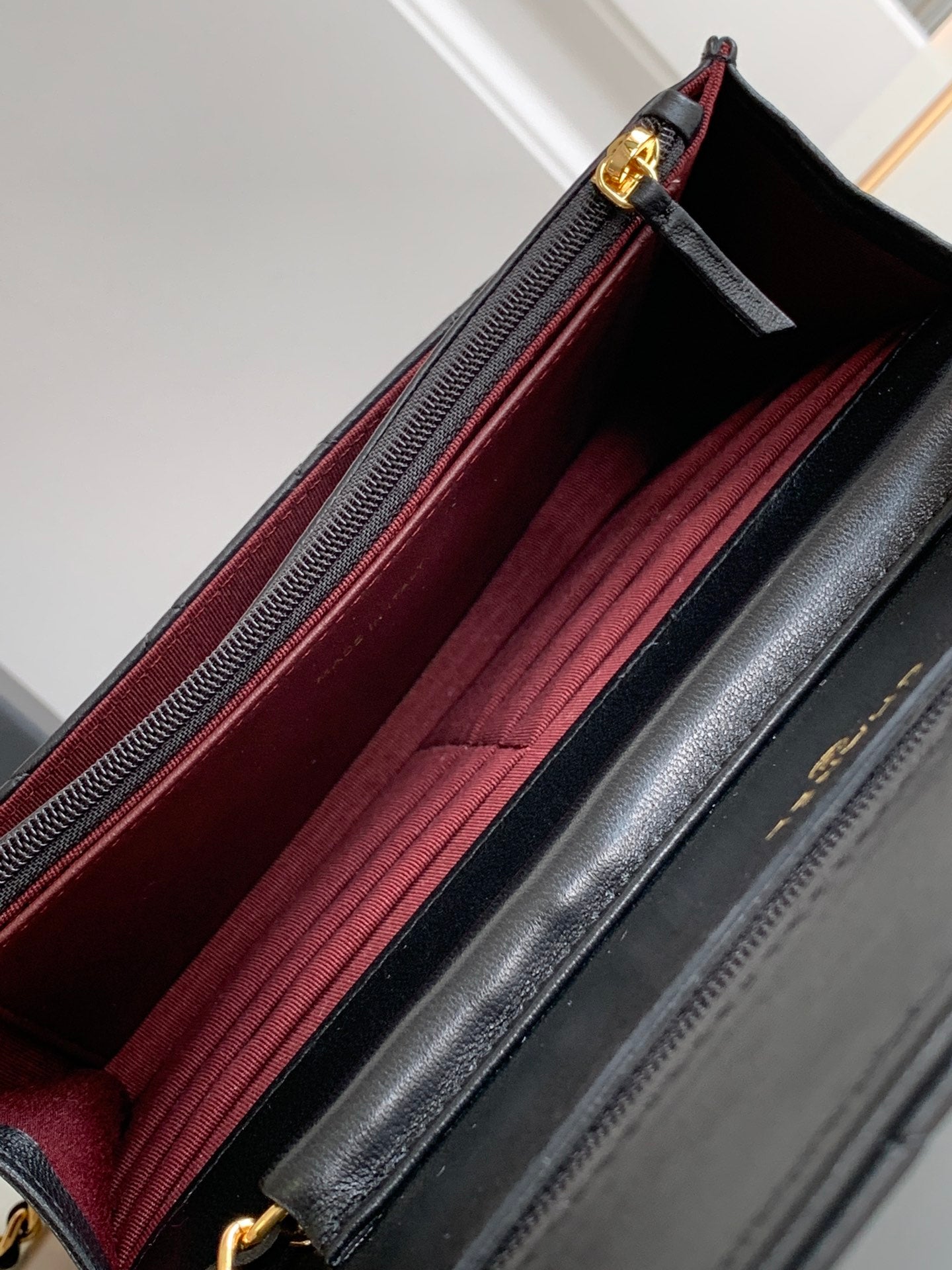 Open black leather bag showing burgundy fabric interior lining and zipper opening