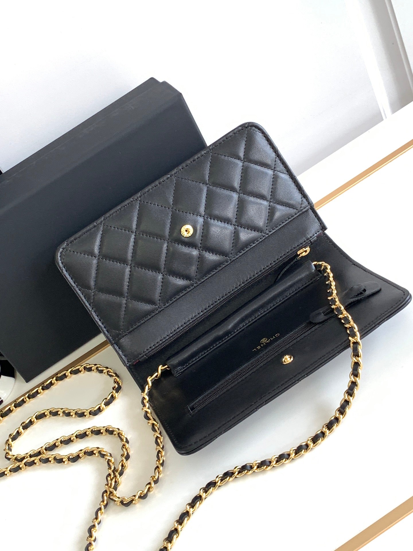 Black leather flap shoulder bag open to reveal compartments and gold-tone hardware