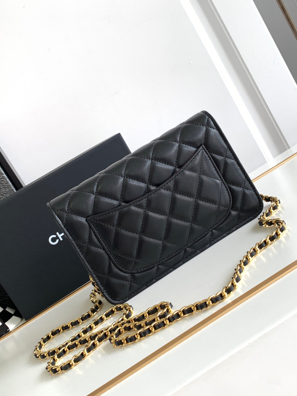 Quilted black leather flap shoulder bag with gold-tone chain strap, front view