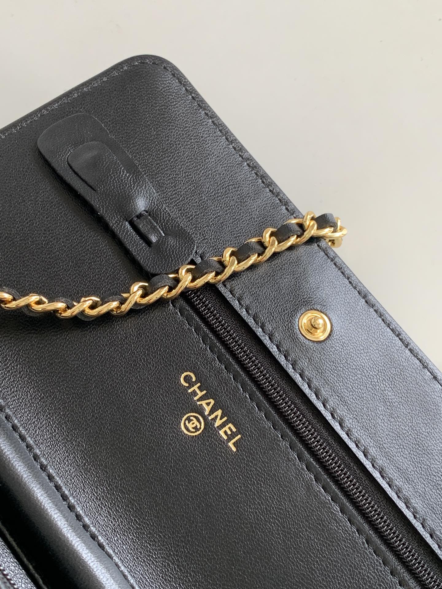 Black leather wristlet-style bag with zipper, gold-tone pull and CHANEL logo detail