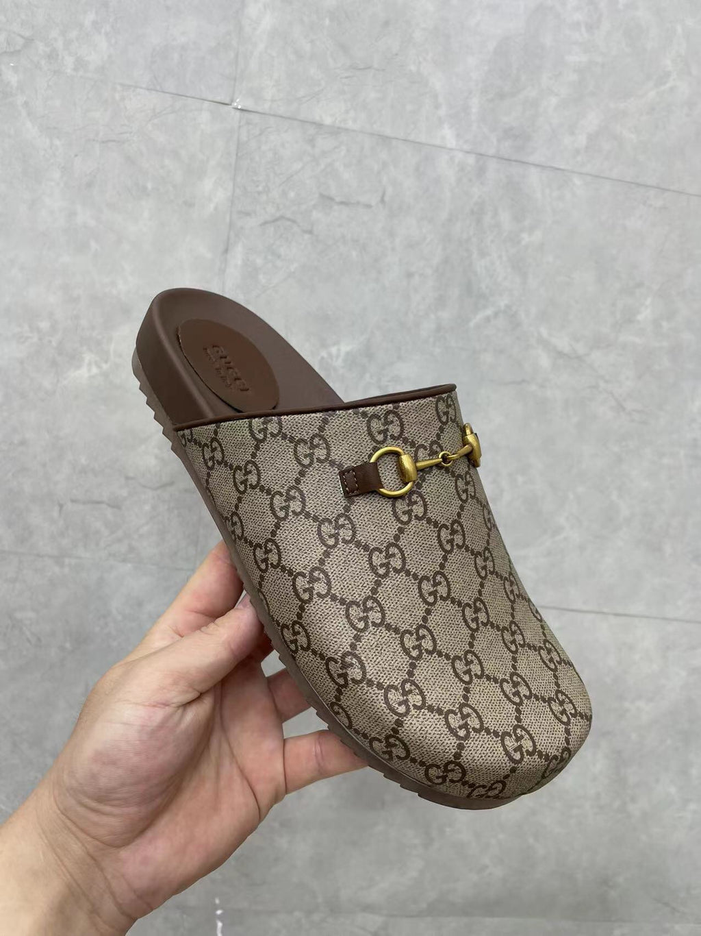 Gucci GG slide sandal in hand, beige canvas with gold buckle and dark brown footbed