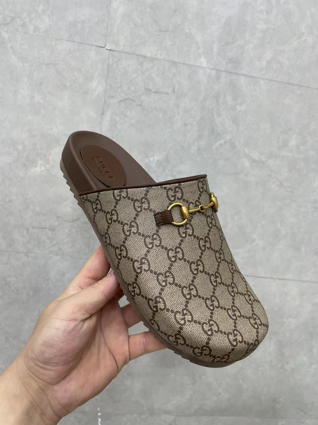 Gucci GG slide sandal in hand, beige canvas with gold buckle and dark brown footbed