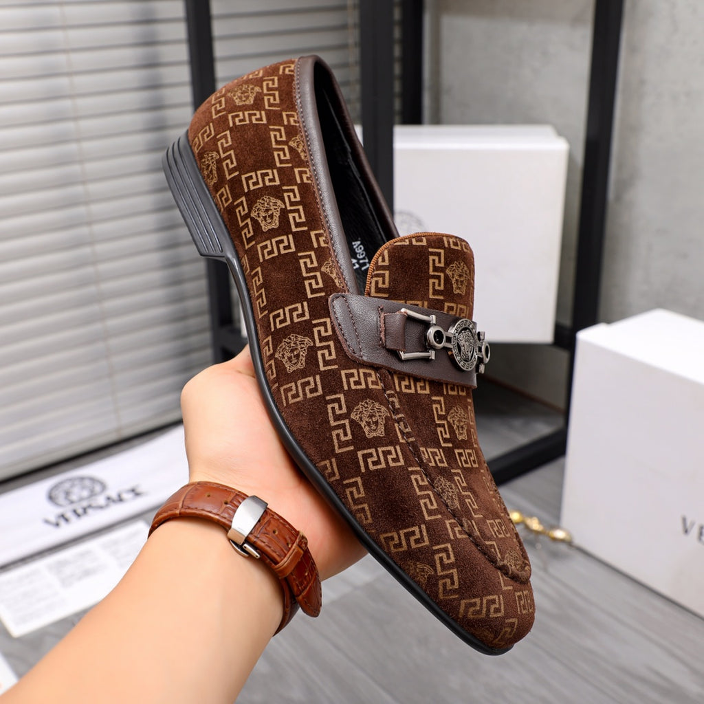 Versace luxury loafers held in hand; brown monogram print and front metal buckle