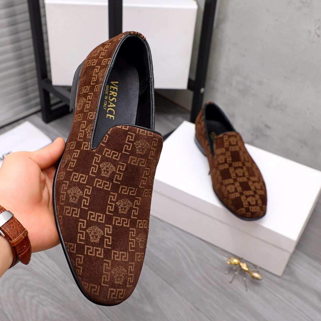 Versace luxury slip-on shoe in brown with repeating logo pattern and black heel trim.