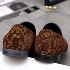 Versace luxury slip-on shoes with brown patterned uppers and black rubber heel sections.