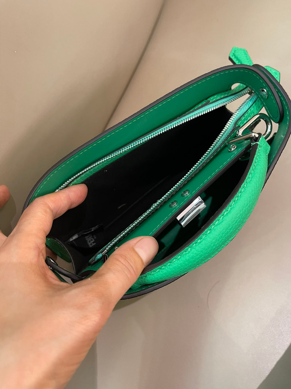 Green Fendi mini handbag opened, showing black lining and interior zip hardware