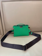 Green mini handbag with top handle, gold clasp, and dark logo shoulder strap