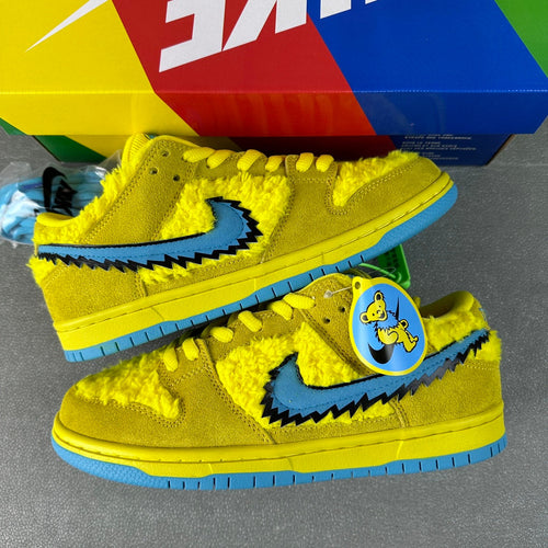 Yellow Nike Dunk SB Low sneakers with blue swoosh graphic and bear patch