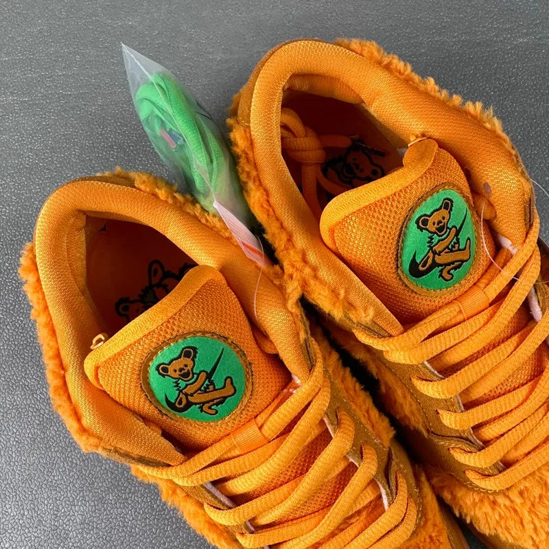 Orange plush low-top sneakers with green bear tongue patches and orange laces