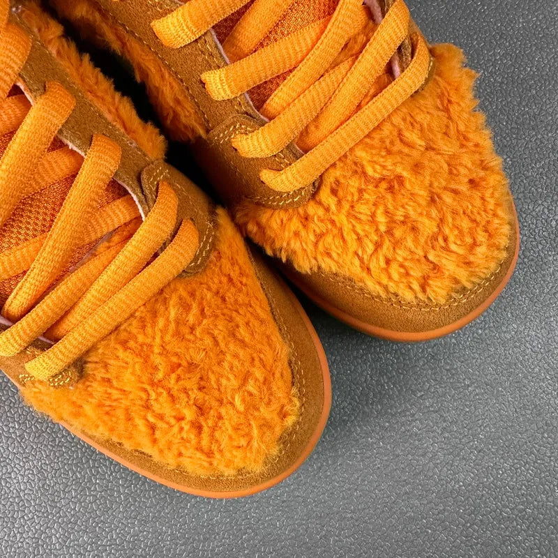 Close-up of orange plush low-top sneakers with orange laces and brown suede panels