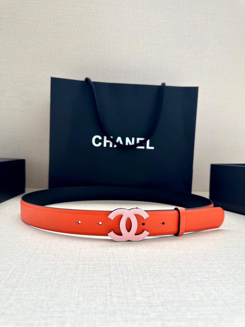 Orange Chanel belt with silver-tone CC buckle on flat leather strap