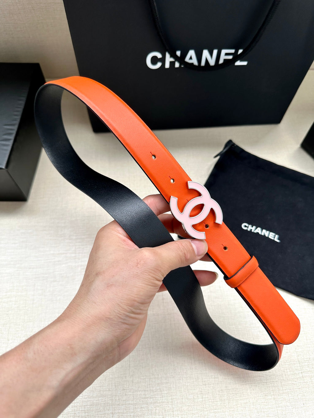 Orange Chanel belt with silver-tone CC buckle and black underside strap