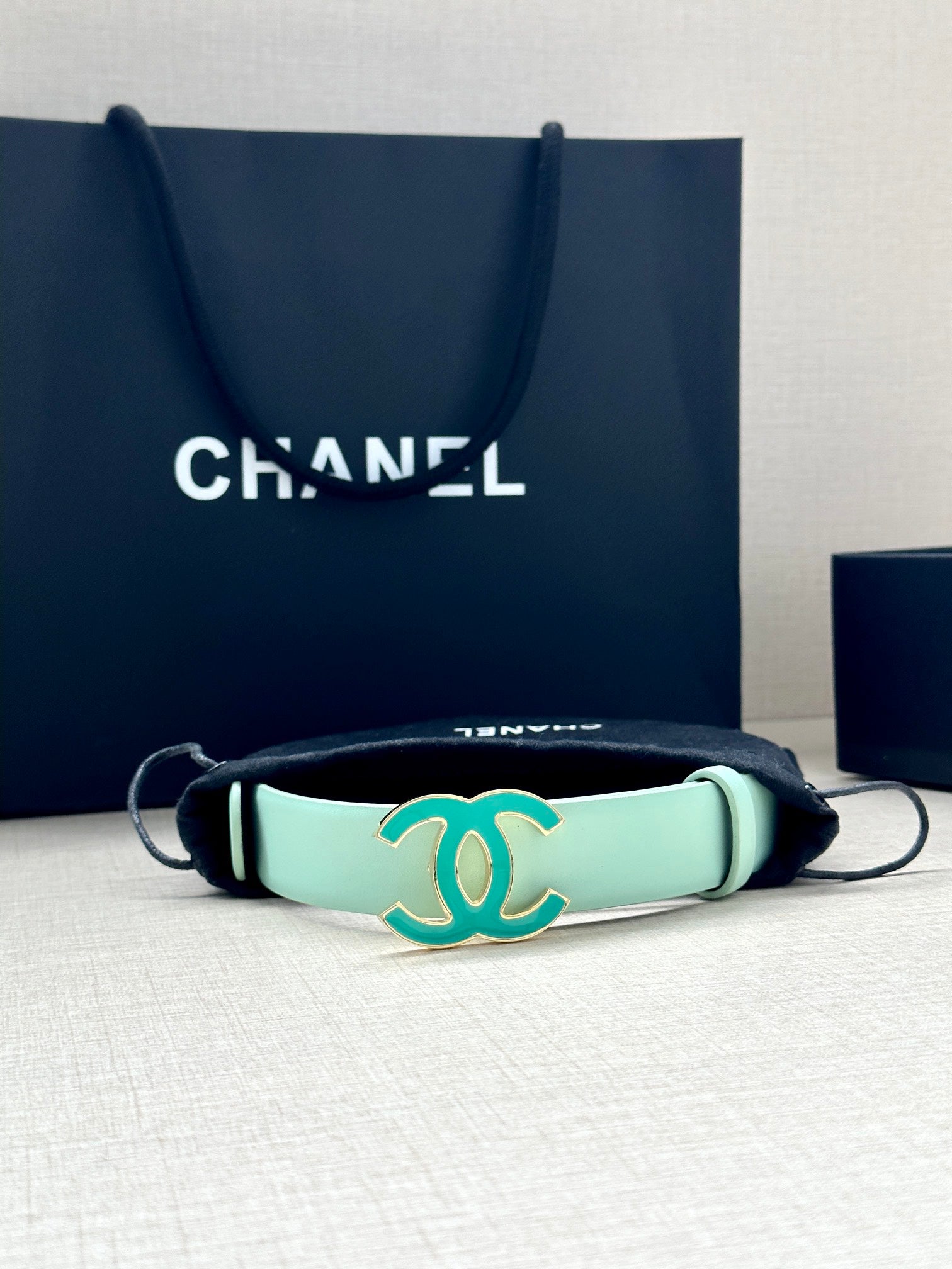 Mint Chanel belt bracelet-style strap with turquoise CC buckle and black cords.