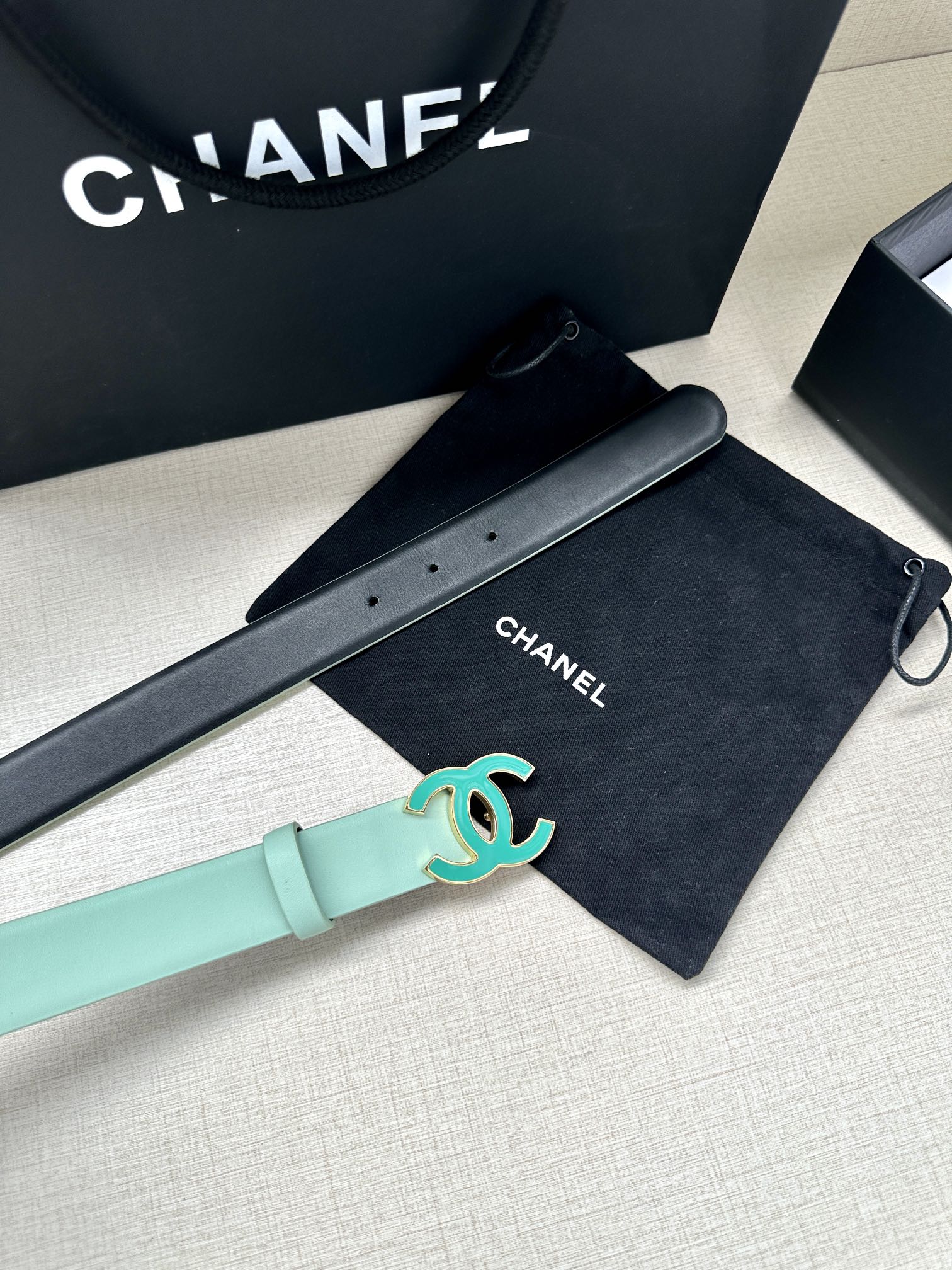 Mint Chanel belt with turquoise CC logo buckle, shown alongside a black belt.