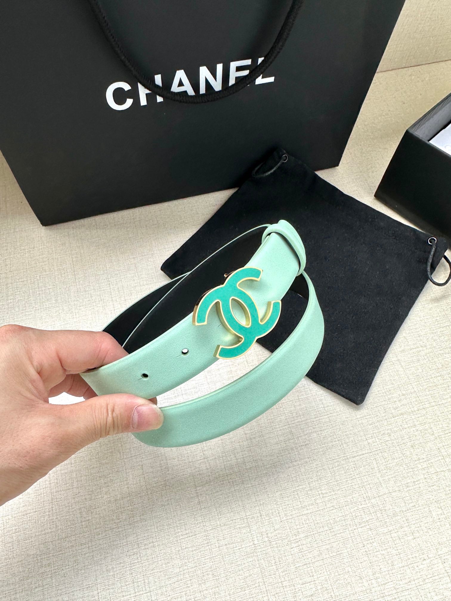 Mint Chanel belt detail with turquoise CC buckle and punched hole strap end.