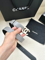 Gray leather belt with gold-tone CC logo buckle, close-up held in hand