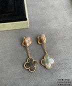 Gold clover drop earrings with dangling chain and pastel blue-green pendant on gray base