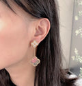 Gold stud earrings with dangling clover charms and pastel pink center stones