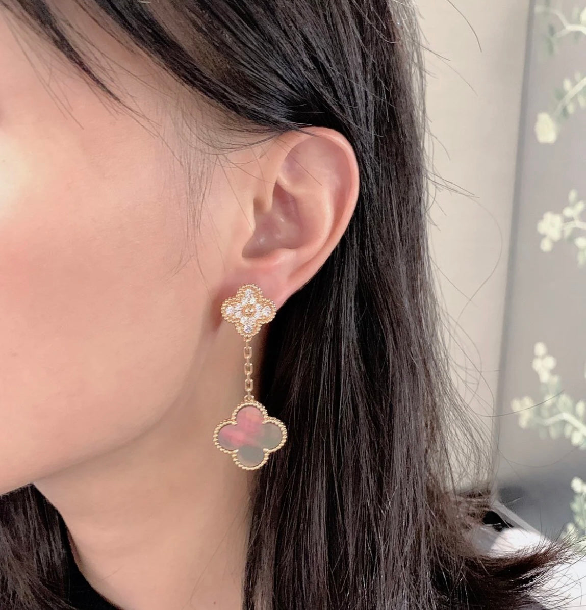 Gold stud earrings with dangling clover charms and pastel pink center stones