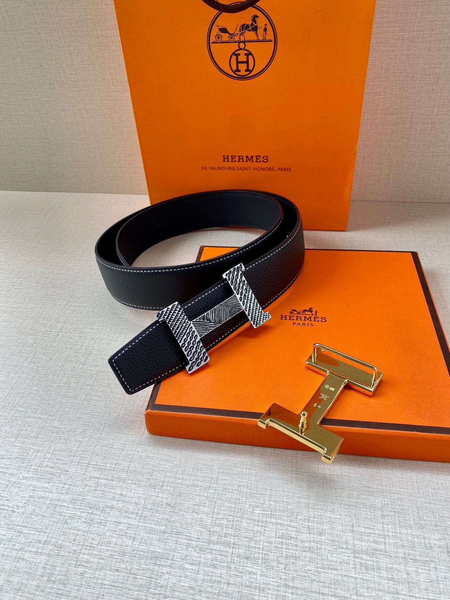 Leather belt with dark blue strap and metal buckle with H clasp, gold-toned