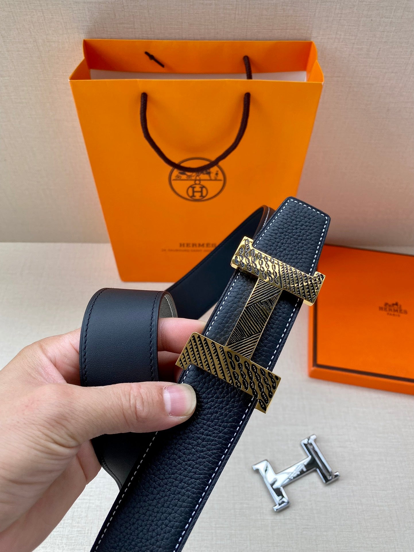Leather belt with dark blue strap and gold-toned interlocking buckle plate