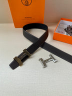 Hermes belt laid flat, dark leather with metal H buckle and patterned strap.