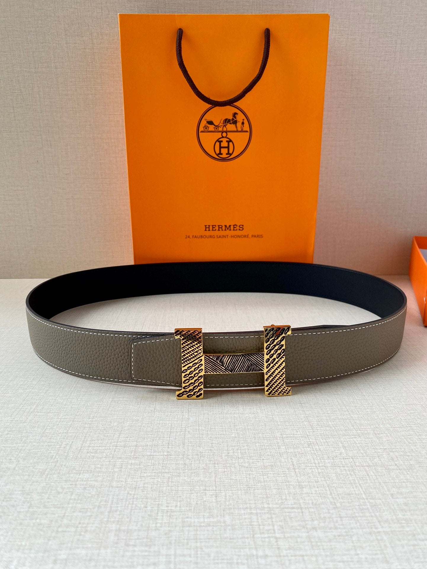 Two-tone leather belt with textured gold-tone clasp, flat on surface