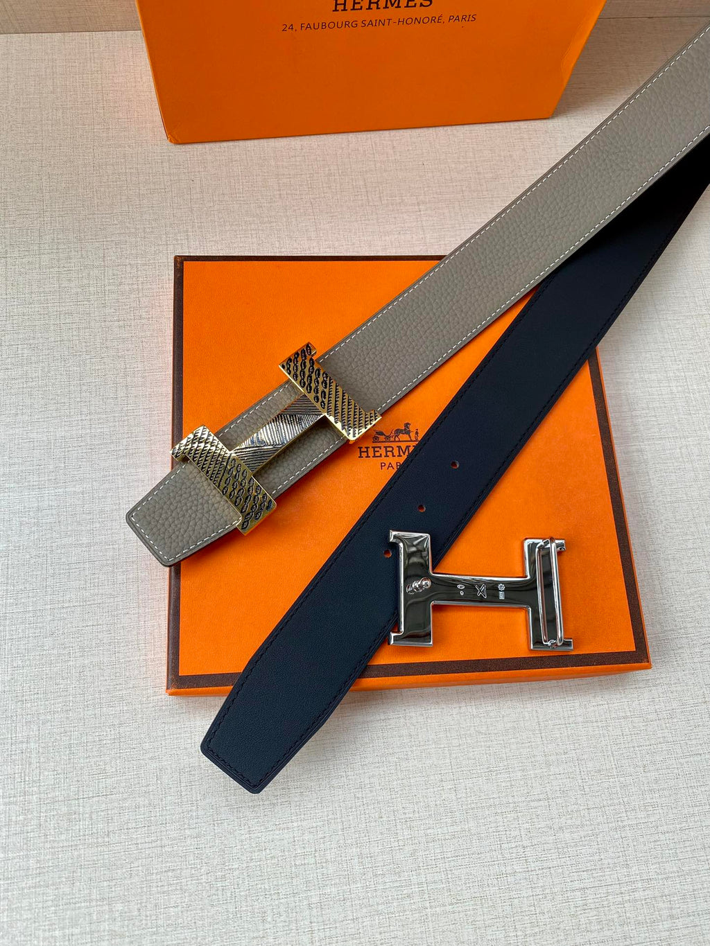 Two-tone leather belt with textured buckle strap and gold-tone clasp, close-up view