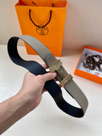 Two-tone leather belt draped in hand; textured center strap with gold-tone clasp