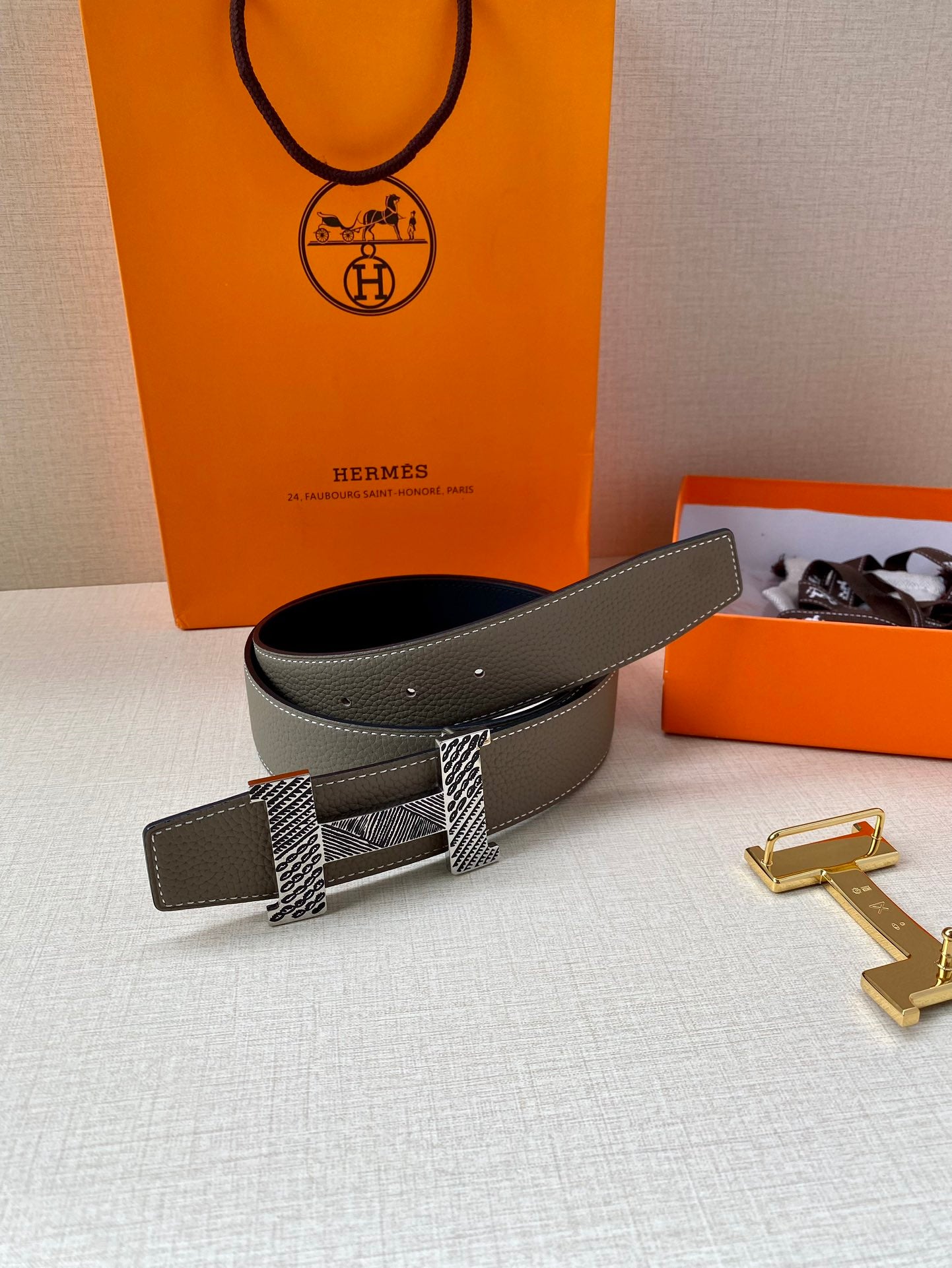 Two-tone leather belt with textured buckle strap and gold-tone clasp, laid flat