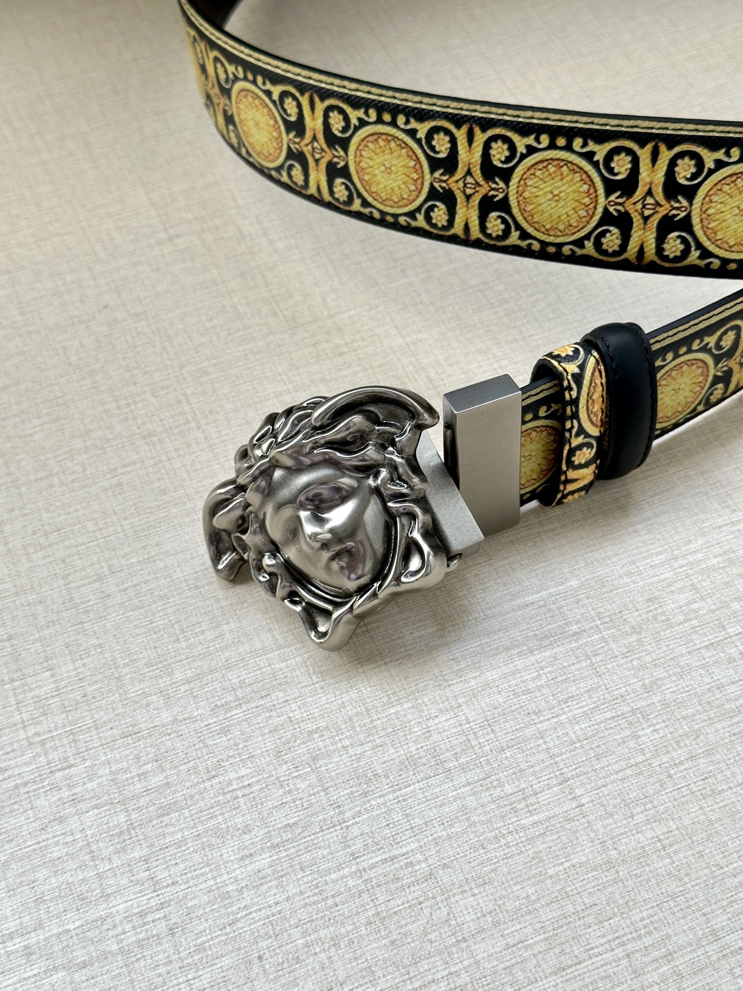 Navy leather belt with gold patterned strap and silver Medusa head buckle