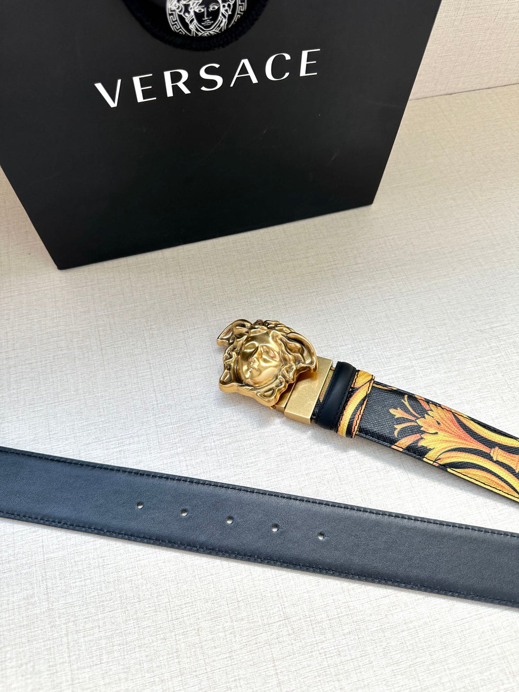 Versace belt with dark blue leather strap, gold buckle, and patterned tip