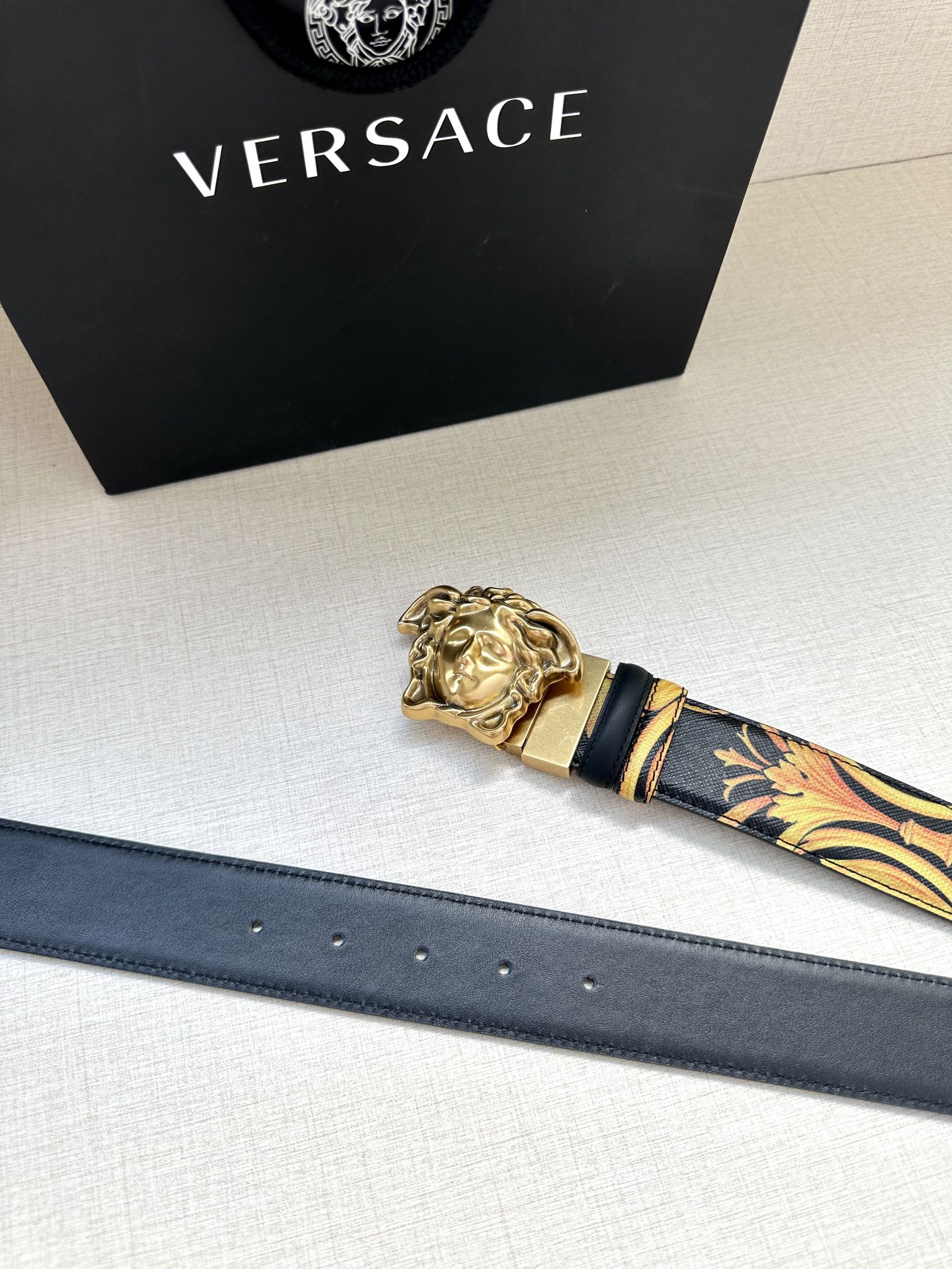 Versace belt with dark blue leather strap, gold buckle, and patterned tip