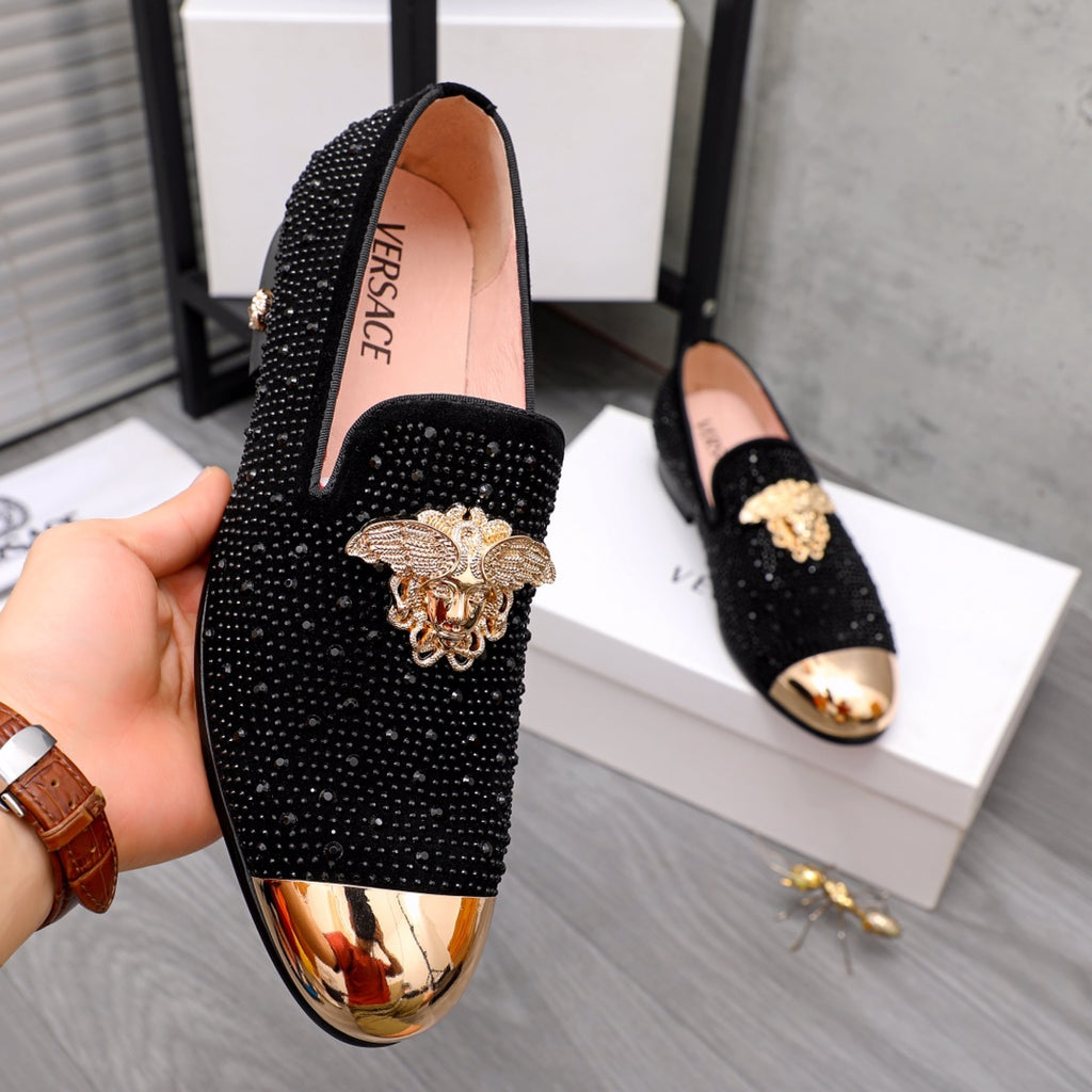 Black jeweled loafers with gold-toned crest ornament and reflective toe trim