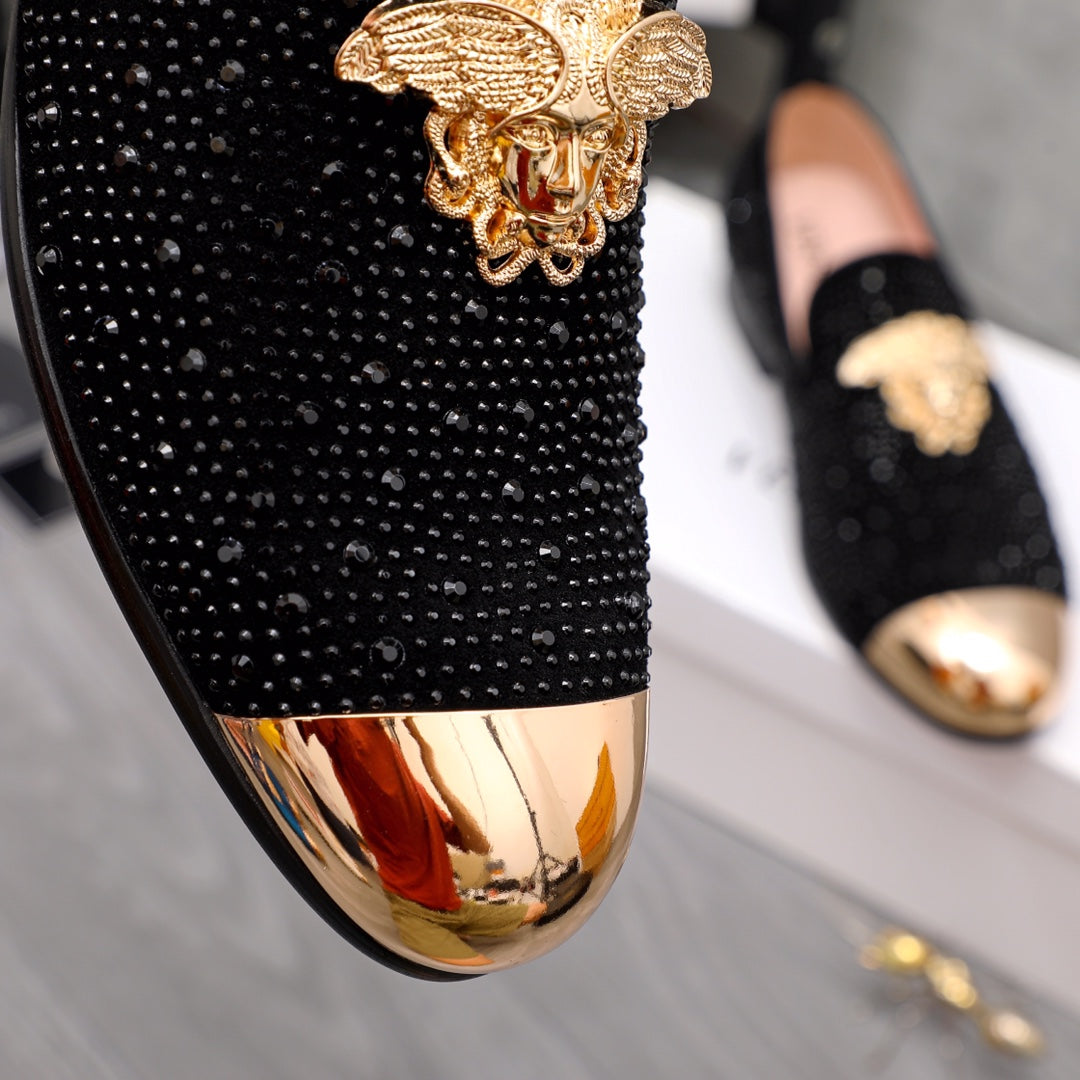 Close-up of black glitter loafer upper with gold-toned crest ornament detail