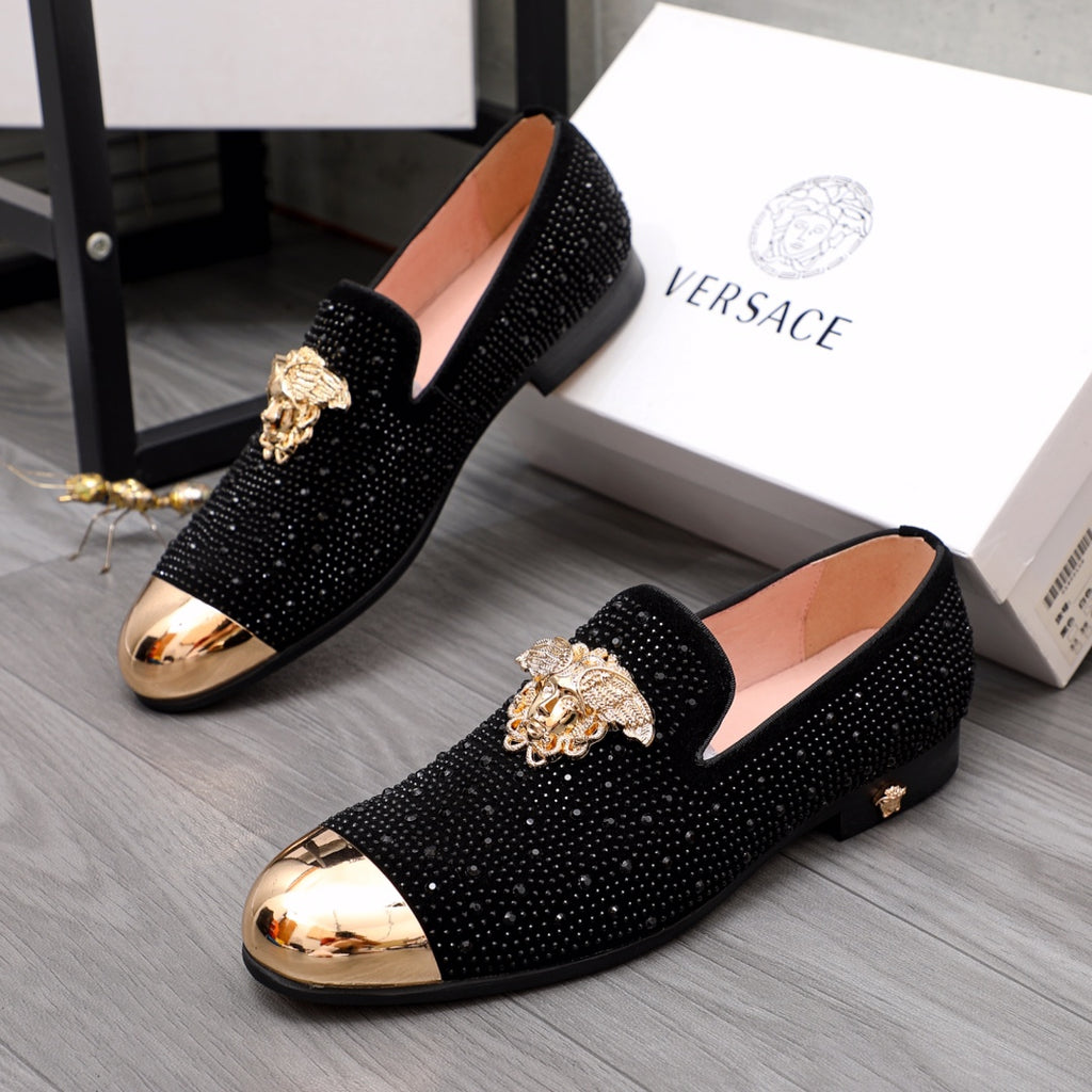 Pair of black glitter loafers with gold-toned crest ornament and curved toe caps