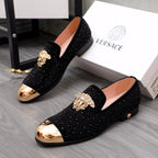 Pair of black glitter loafers with gold-toned crest ornament and curved toe caps