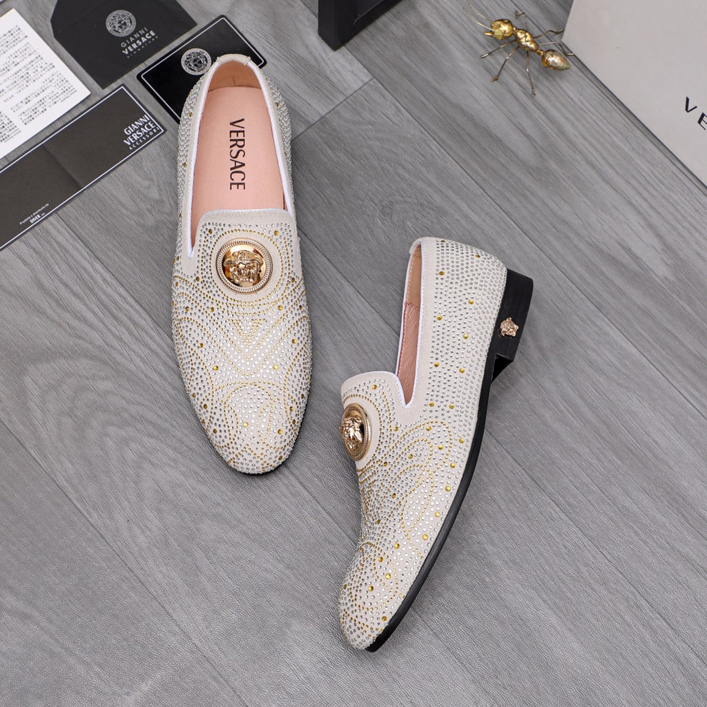 Two white studded slip-on loafers with gold medallion accents, top-down view