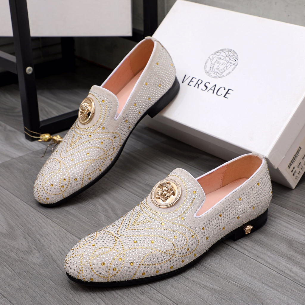Pair of white studded slip-on loafers with gold round medallion accents and dark trim