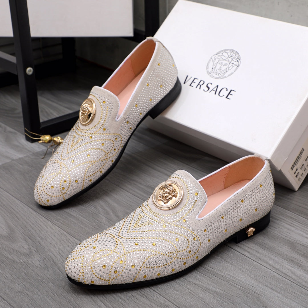 Pair of white studded slip-on loafers with gold round medallion accents and dark trim
