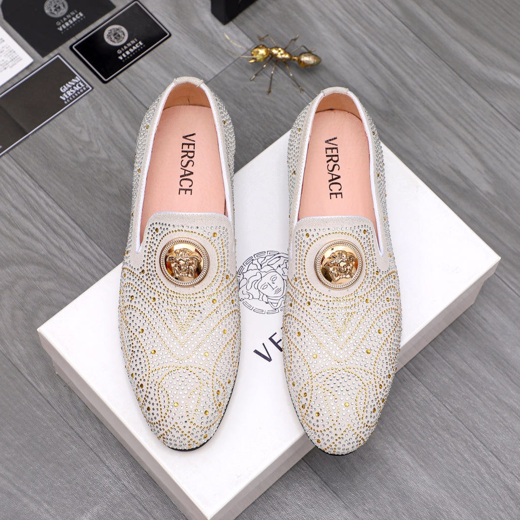 Embellished white slip-on loafer with gold-tone stud pattern and round medallion accent