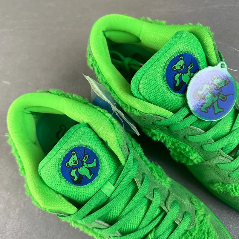 Pair of green sneakers with blue embroidered tongue patches and green lace-up uppers