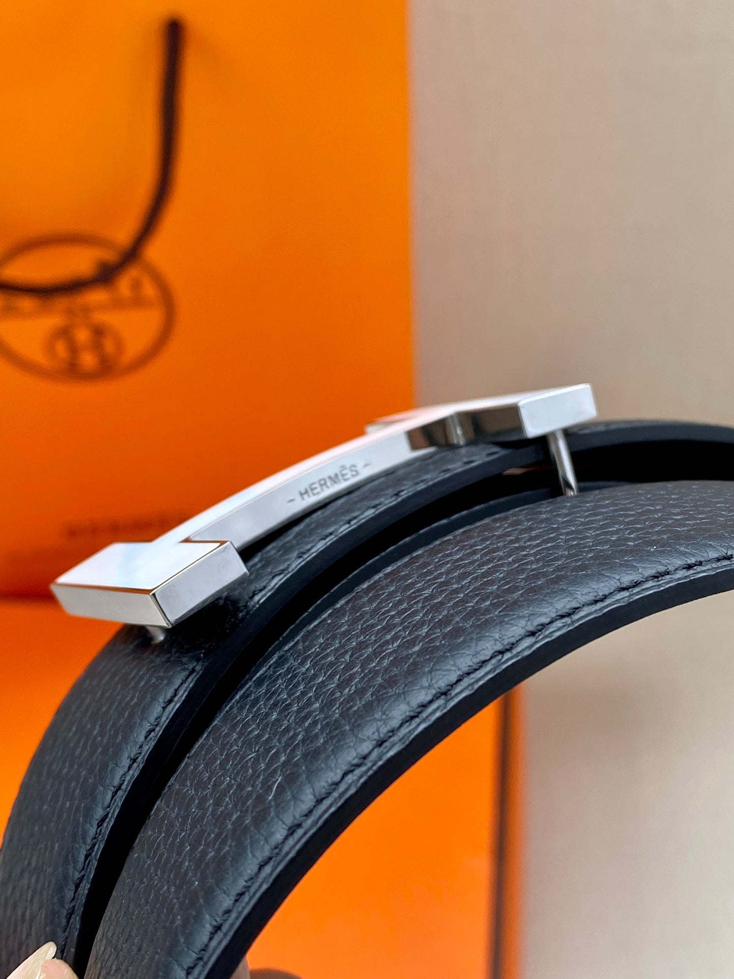 Dark blue leather belt close-up of silver buckle bar and keeper