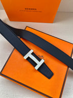 Dark blue leather belt with silver H buckle resting on orange packaging