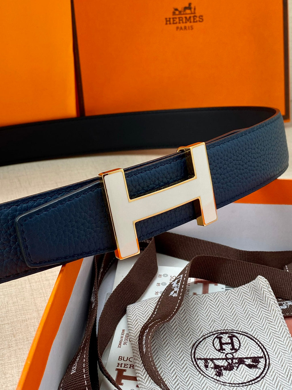 Blue leather belt with silver H buckle and textured strap, laid flat.